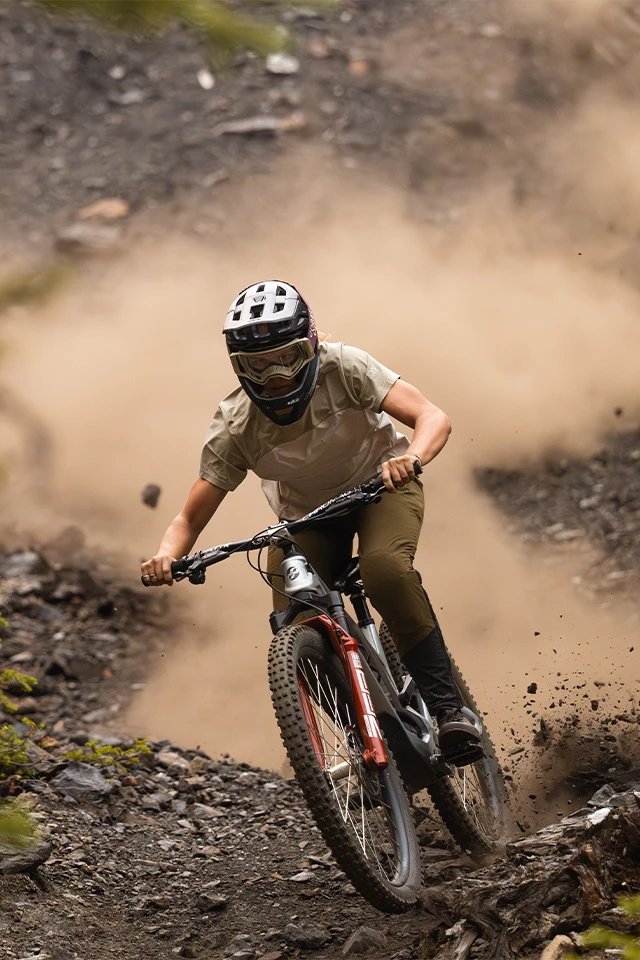 Mountain biker jumps over light-colored rocks, wearing mtb helmet Targon © ABUS
