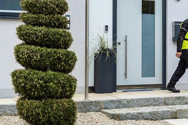 Egy fekete motoros overallban lévő férfi kilép a házából, és odamegy a nyitott garázs előtt álló motorjához. ©ABUS