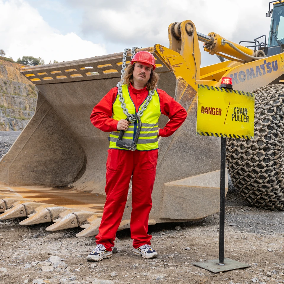 In einem Steinbruch präsentiert Robert Lindemann das Bügelschloss GRANIT Super Extreme 2500 vor einem Radlader. ©ABUS