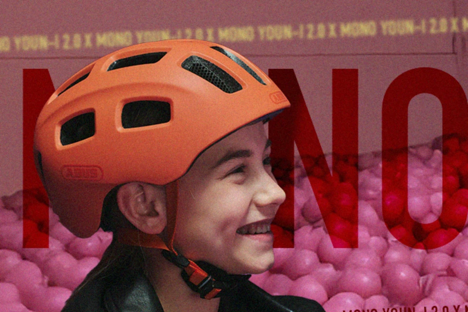 Lächelndes Mädchen mit dem Kinderhelm YOUN-I 2.0 in der Farbe Mono orange © ABUS