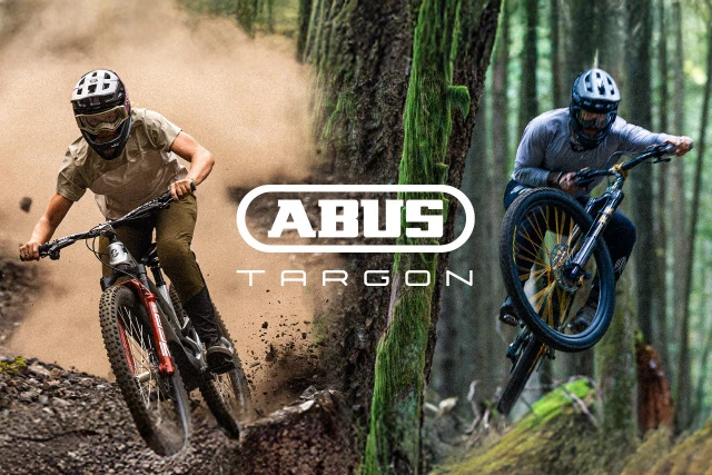 Casque VTT « TARGON » avec logo en gros plan, tandis qu’un vététiste roule à l’arrière-plan sur un terrain poussiéreux © ABUS