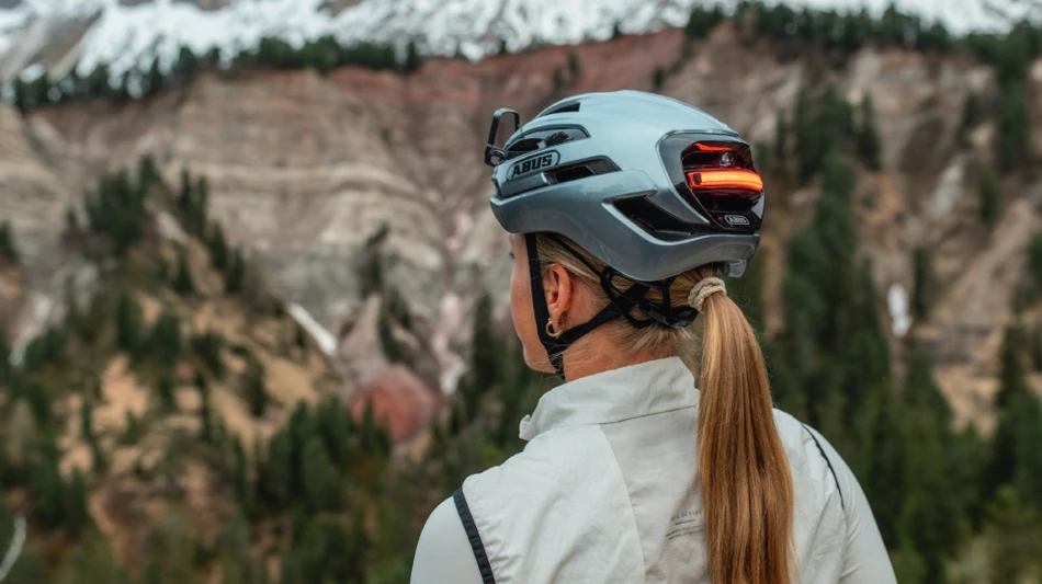 Frau mit blonden langen Haaren tr&auml;gt Taipan LED graphit silver und schaut in eine Berglandschaft &copy; ABUS