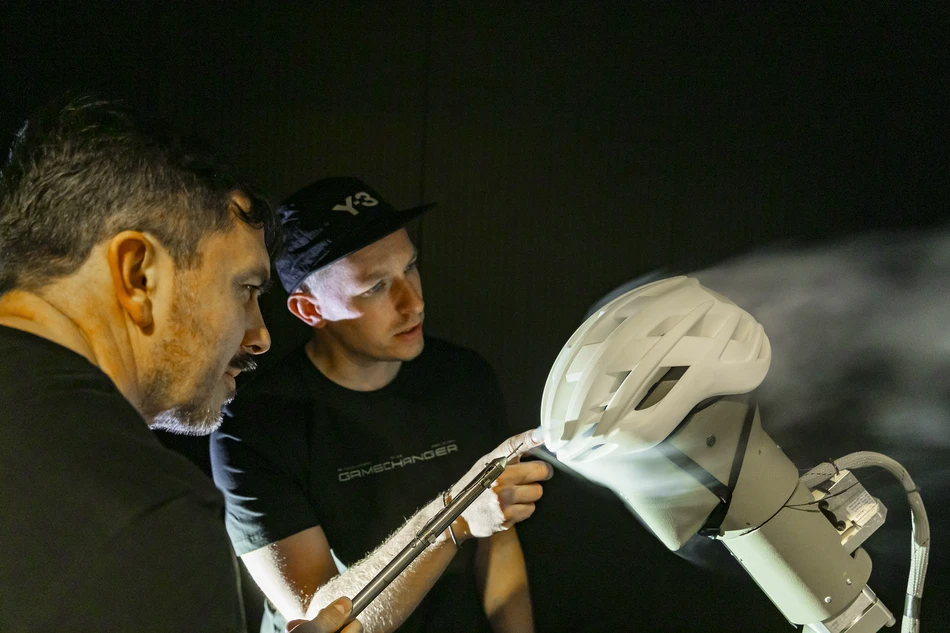 Two product developers test the aerodynamics of the AirBreaker 2.0 in the wind tunnel, the airflow is visible &copy; ABUS