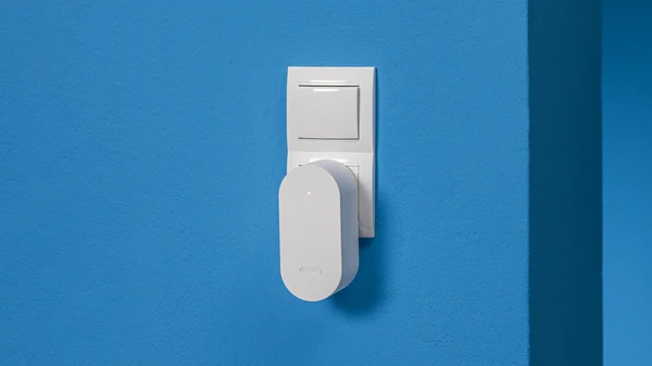 BRIDGE One in white plugged into a socket on a blue wall &copy; ABUS