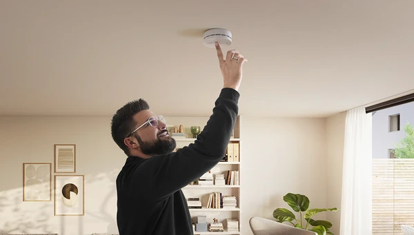 Mann dr&uuml;ckt Taste auf dem PREFIRA 10 Rauchmelder an der Decke &copy; ABUS